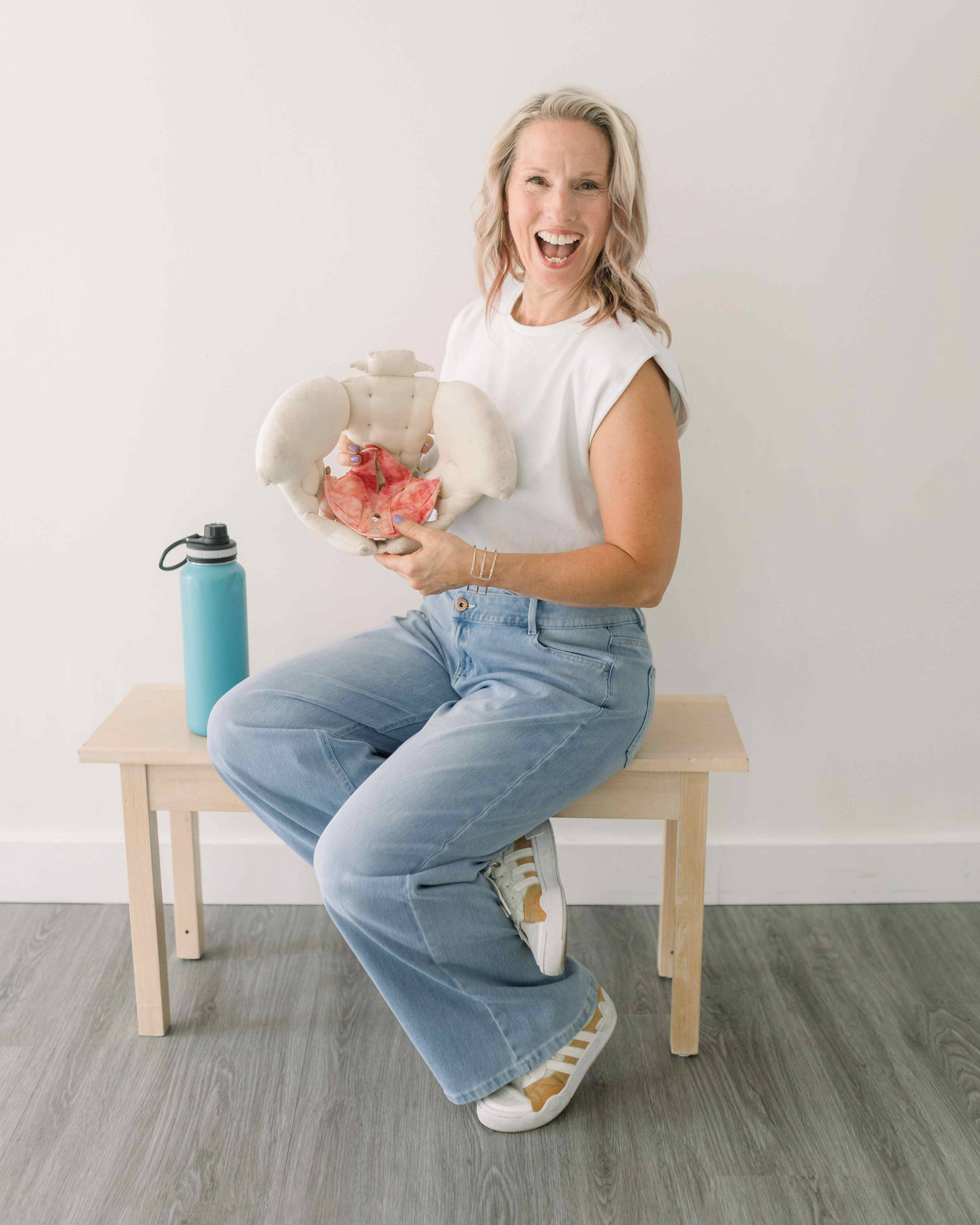 Kristen Parise laughing, holding a pelvic anatomy model